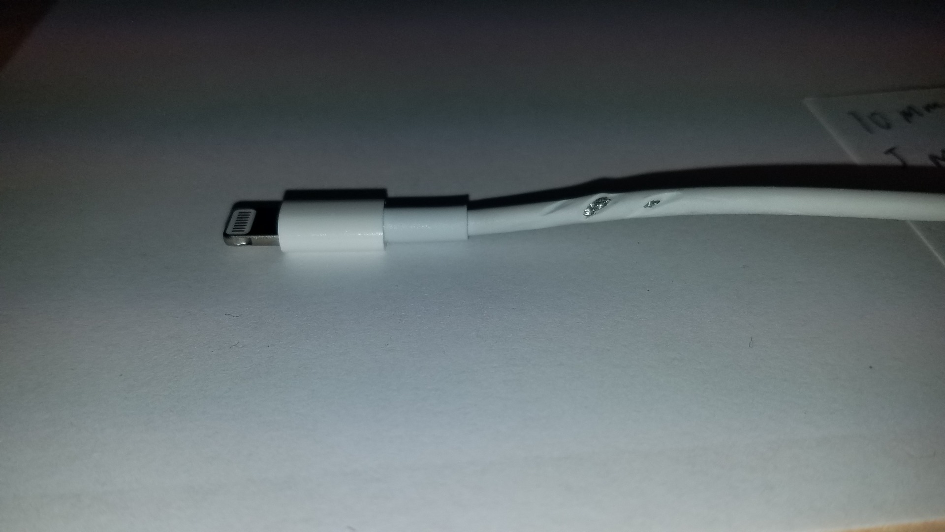 A broken iPhone charging cable that is about to be fixed using heat shrink tubing.